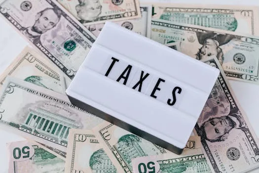 pexels-photo-4386367-4386367 US dollar bills surrounding a sign showing 'TAXES'. Ideal for financial context.