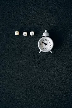 pexels-photo-6863256-6863256 Miniature clock and word tax on black background symbolizing tax season deadlines.